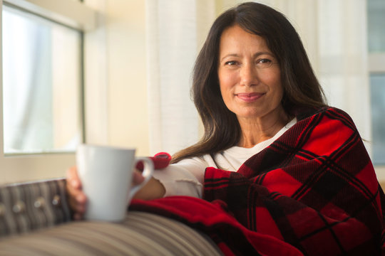 Mature Hispanic woman at home drinking coffee.