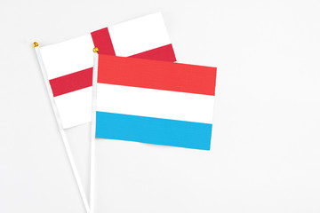 Luxembourg and England stick flags on white background. High quality fabric, miniature national flag. Peaceful global concept.White floor for copy space.