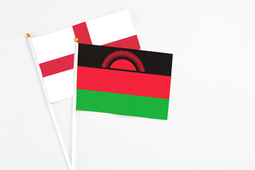 Malawi and England stick flags on white background. High quality fabric, miniature national flag. Peaceful global concept.White floor for copy space.