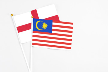 Malaysia and England stick flags on white background. High quality fabric, miniature national flag. Peaceful global concept.White floor for copy space.