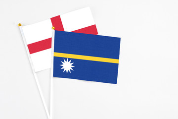 Nauru and England stick flags on white background. High quality fabric, miniature national flag. Peaceful global concept.White floor for copy space.