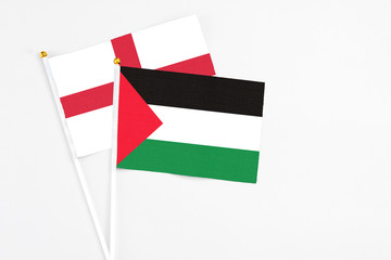 Palestine and England stick flags on white background. High quality fabric, miniature national flag. Peaceful global concept.White floor for copy space.