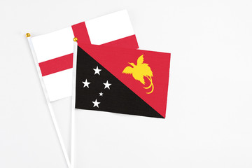 Papua New Guinea and England stick flags on white background. High quality fabric, miniature national flag. Peaceful global concept.White floor for copy space.