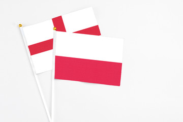 Poland and England stick flags on white background. High quality fabric, miniature national flag. Peaceful global concept.White floor for copy space.