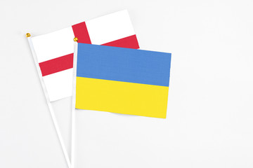 Ukraine and England stick flags on white background. High quality fabric, miniature national flag. Peaceful global concept.White floor for copy space.
