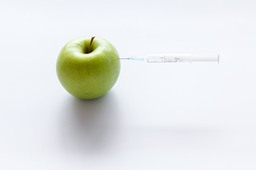 Beauty injection concept. Syringe and green apple on white background copy space