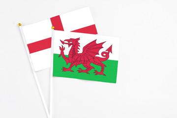 Wales and England stick flags on white background. High quality fabric, miniature national flag. Peaceful global concept.White floor for copy space.