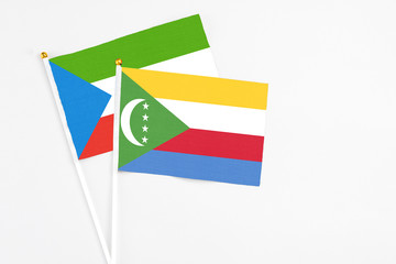Comoros and Equatorial Guinea stick flags on white background. High quality fabric, miniature national flag. Peaceful global concept.White floor for copy space.