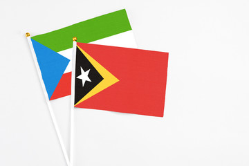 East Timor and Equatorial Guinea stick flags on white background. High quality fabric, miniature national flag. Peaceful global concept.White floor for copy space.