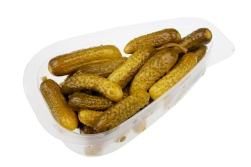 Daily food product - small pickled green gherkins cucumbers  in a transparent plastic container  isolated macro