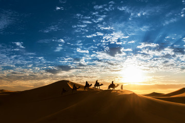 Fototapeta na wymiar Caravan in the desert during sunrise against a beautiful cloudy sky.