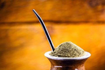 Yerba mate tea in wooden bowl on wooden table. Traditional drink from Brazil, Argentina, Paraguay...