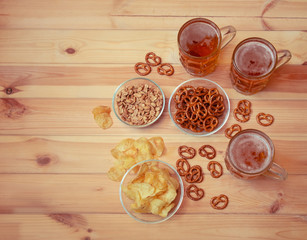 Mugs of light  beer with potato chips, salted pretzels and peanuts. Top view, copy space.