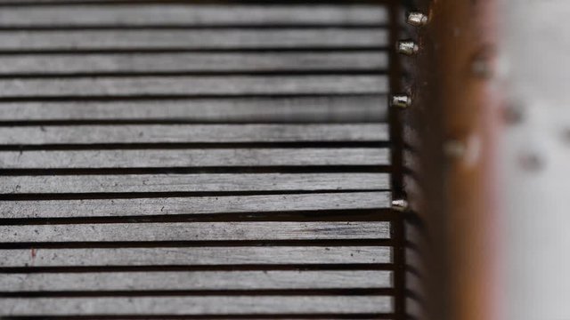 Macro close-up of the inside of a vintage music box as the drum spins and the tiny teeth pluck the comb to play notes, 50fps.