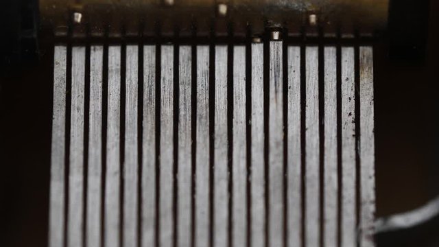 Top-down macro view of the inside of an old music box as drum spins and the tiny pins pluck the teeth of the comb.