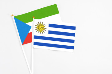 Uruguay and Equatorial Guinea stick flags on white background. High quality fabric, miniature national flag. Peaceful global concept.White floor for copy space.