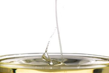 splash of yellow vegetable oil in a bowl on a white background