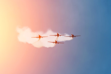 Four light-engine aircraft fly from far away leaving a smoky trail.