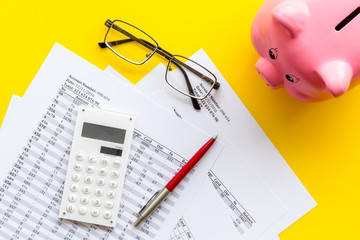 Taxes payment concept. Financial documents, piggy bank, calculator on yellow background top view