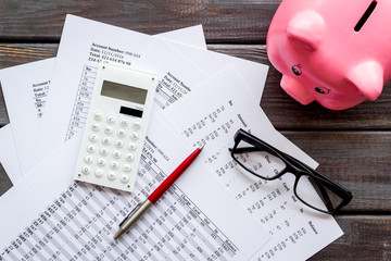 Taxes payment concept. Financial documents, piggy bank, calculator on dark wooden background top...