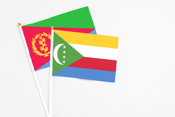 Comoros and Eritrea stick flags on white background. High quality fabric, miniature national flag. Peaceful global concept.White floor for copy space.
