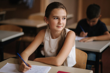 Boy and girl sitting at desk and writing a text