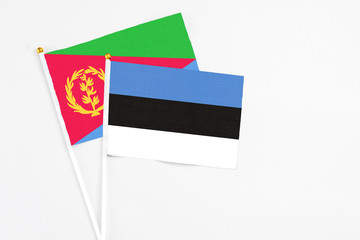 Estonia and Eritrea stick flags on white background. High quality fabric, miniature national flag. Peaceful global concept.White floor for copy space.