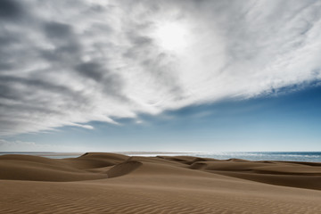 Desert sand dunes at Lac Naila with dark cloudy sky.