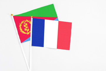 France and Eritrea stick flags on white background. High quality fabric, miniature national flag. Peaceful global concept.White floor for copy space.
