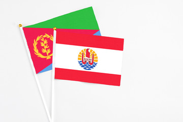 French Polynesia and Eritrea stick flags on white background. High quality fabric, miniature national flag. Peaceful global concept.White floor for copy space.