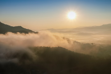 Mountain view morning of soft mist moving around top hill with sea of fog and yellow sun light in the sky background, sunrise at Wat Tha Ton, Tha Ton, Fang, Chiang Mai, Thailand.