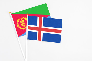 Iceland and Eritrea stick flags on white background. High quality fabric, miniature national flag. Peaceful global concept.White floor for copy space.