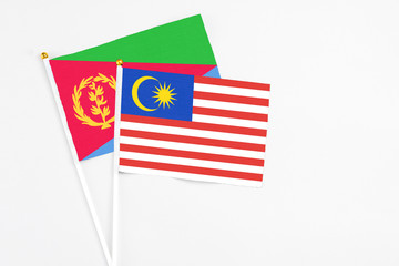 Malaysia and Eritrea stick flags on white background. High quality fabric, miniature national flag. Peaceful global concept.White floor for copy space.