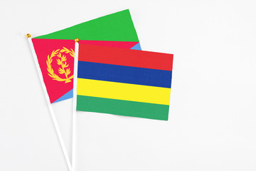 Mauritius and Eritrea stick flags on white background. High quality fabric, miniature national flag. Peaceful global concept.White floor for copy space.