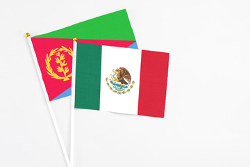 Mexico and Eritrea stick flags on white background. High quality fabric, miniature national flag. Peaceful global concept.White floor for copy space.