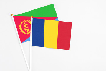 Romania and Eritrea stick flags on white background. High quality fabric, miniature national flag. Peaceful global concept.White floor for copy space.