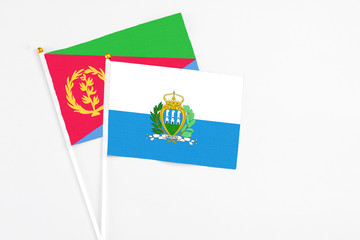 San Marino and Eritrea stick flags on white background. High quality fabric, miniature national flag. Peaceful global concept.White floor for copy space.