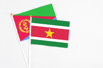 Suriname and Eritrea stick flags on white background. High quality fabric, miniature national flag. Peaceful global concept.White floor for copy space.