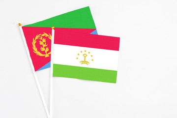 Tajikistan and Eritrea stick flags on white background. High quality fabric, miniature national flag. Peaceful global concept.White floor for copy space.