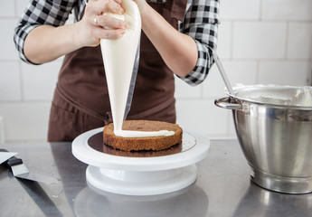 Fototapeta na wymiar Female pastry chef making sponge cake with custard cream vanilla cream on a rack