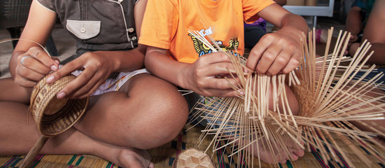 Two Asian girls made bamboo basketry.