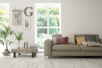 Stylish room in white color with sofa and summer landscape in window. Scandinavian interior design. 3D illustration
