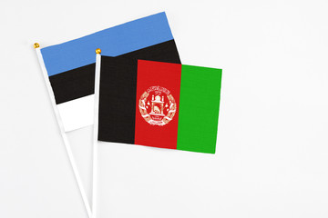 Afghanistan and Estonia stick flags on white background. High quality fabric, miniature national flag. Peaceful global concept.White floor for copy space.