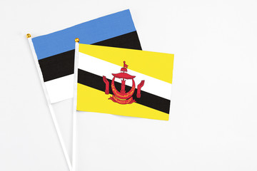 Brunei and Estonia stick flags on white background. High quality fabric, miniature national flag. Peaceful global concept.White floor for copy space.