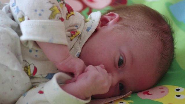 newborn baby lies on a green sheet and looks around
