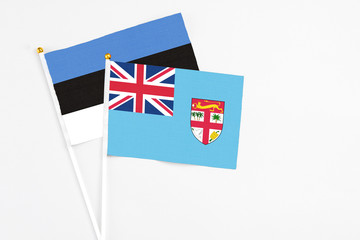 Fiji and Estonia stick flags on white background. High quality fabric, miniature national flag. Peaceful global concept.White floor for copy space.