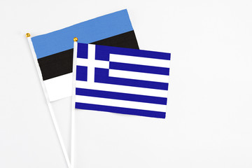Greece and Estonia stick flags on white background. High quality fabric, miniature national flag. Peaceful global concept.White floor for copy space.