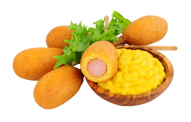 Mini party corn dogs on wooden sticks with a wooden bowl of American mustard isolated on a white background