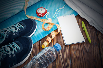 Healthy lifestyle and sports background. Sports shoes, Notepad and pen, stopwatch and water bottle on wooden background with copyspace, top view.