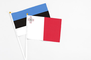 Malta and Estonia stick flags on white background. High quality fabric, miniature national flag. Peaceful global concept.White floor for copy space.